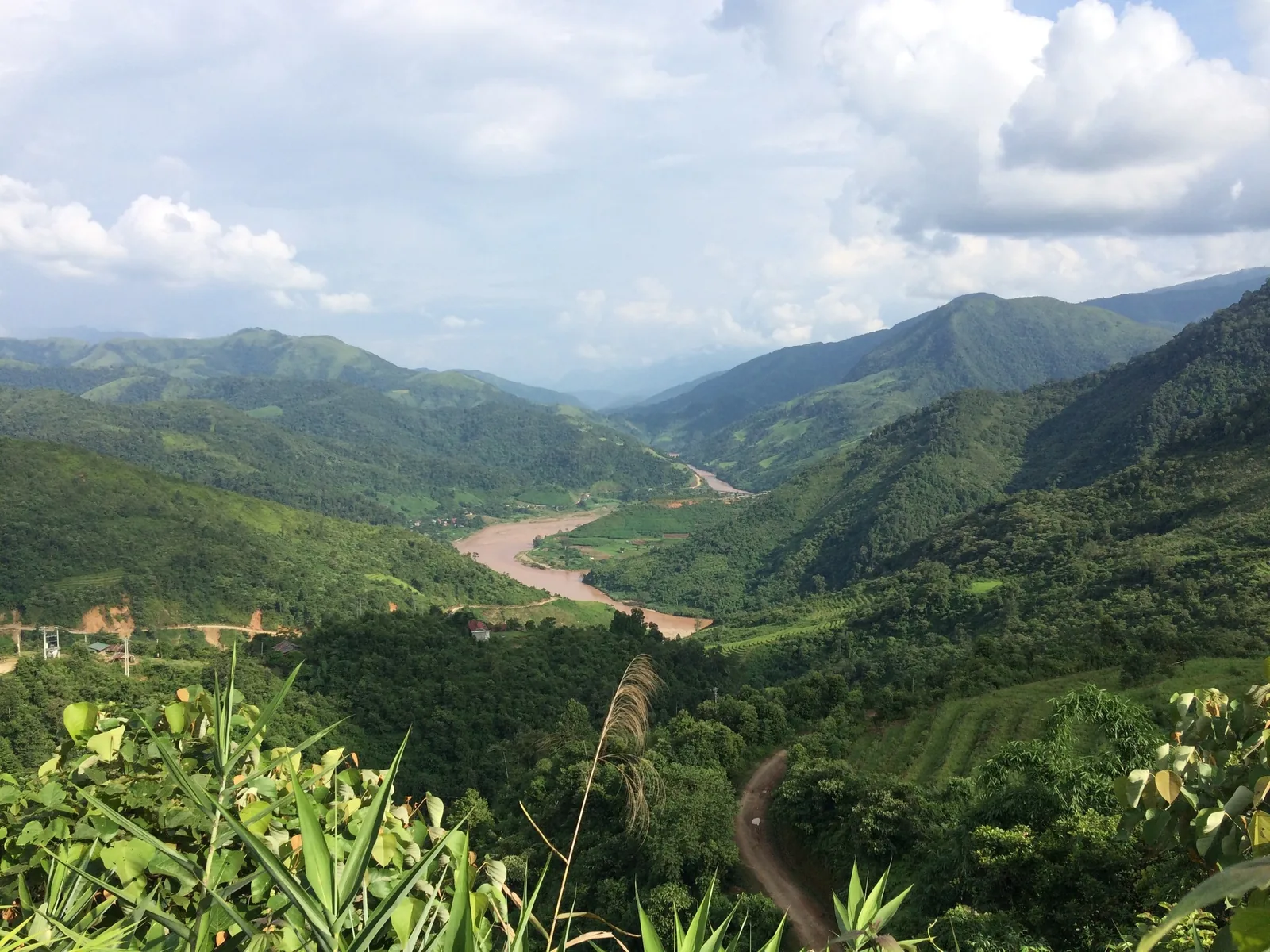 A muddy river winds through a lush green mountain valley near Muong Te in Lai Chau province, Vietnam.