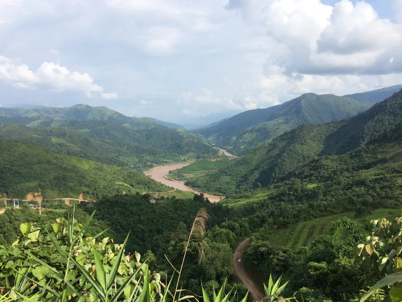 A muddy river winds through a lush green mountain valley near Muong Te in Lai Chau province, Vietnam.