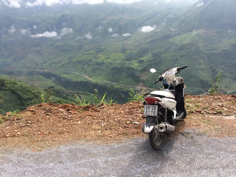 A motorbike parked on a mountain road overlooking green terraced valleys in Lai Chau, Vietnam.