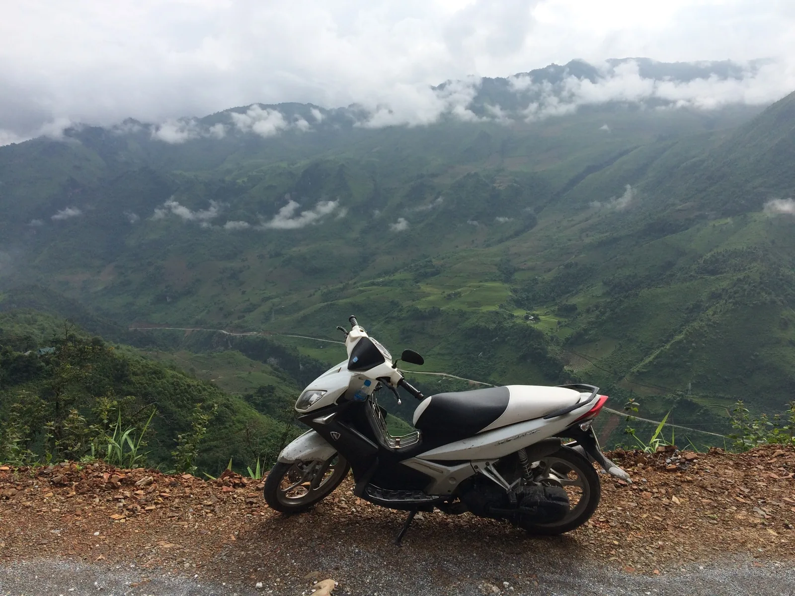 A parked motorbike overlooks misty green mountains along a roadside in Lai Chau, Vietnam.