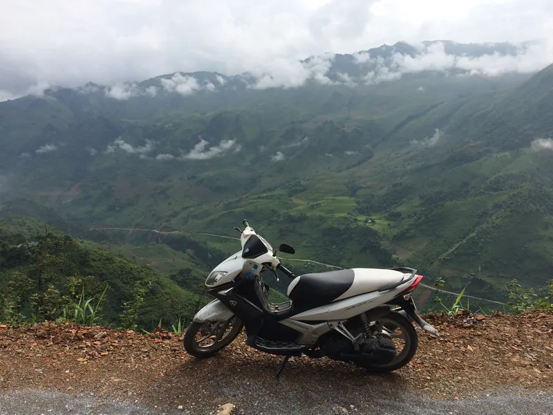 A parked motorbike overlooks misty green mountains along a roadside in Lai Chau, Vietnam.
