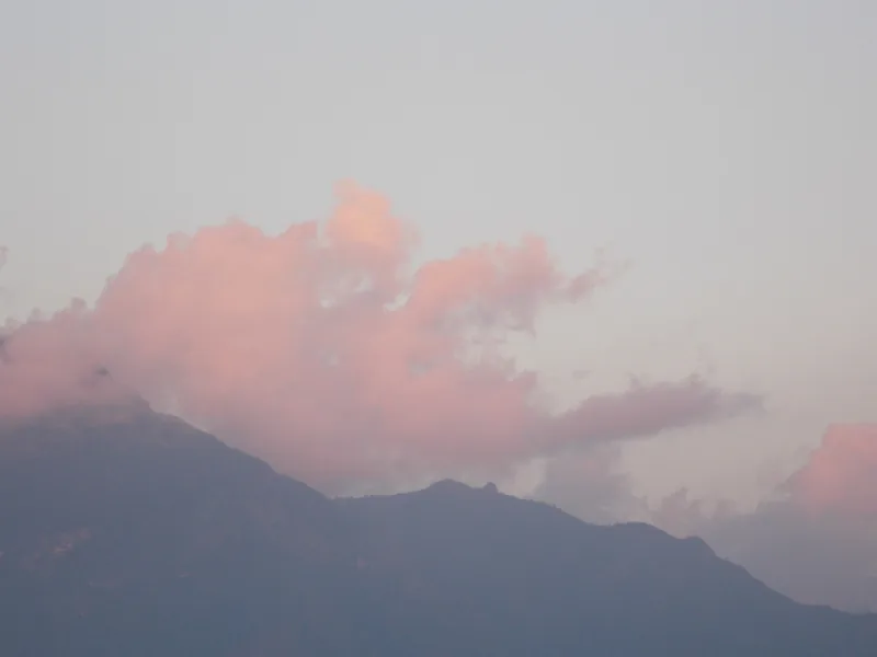 Pink-tinged clouds drift over a mountain silhouette at dusk in Lai Chau, Vietnam.