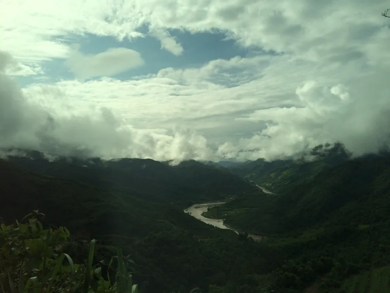 A river winds through misty green mountains under a cloudy sky in Lai Chau, Vietnam.