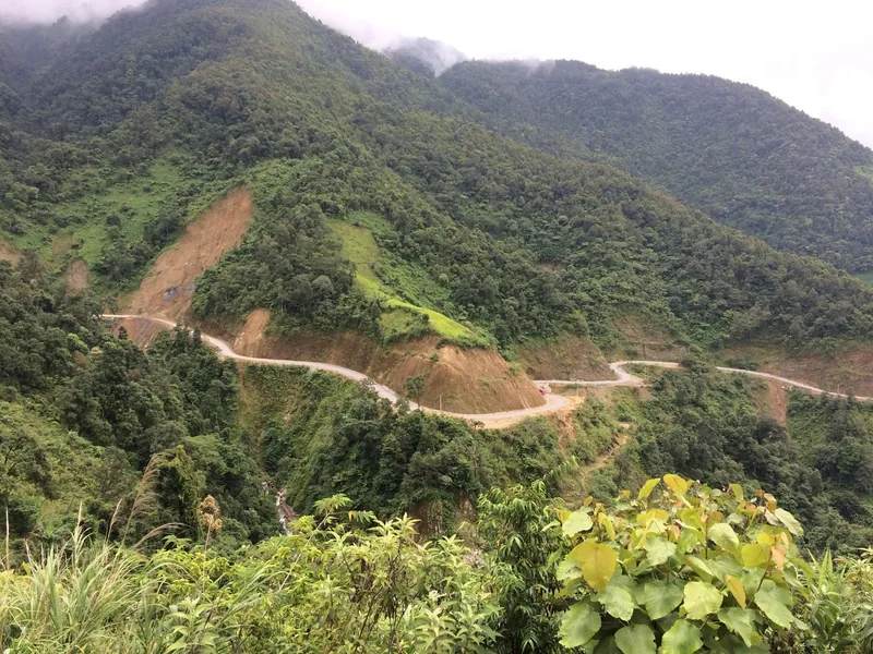 A winding mountain road cuts through green forested hills in Lai Chau, Vietnam.