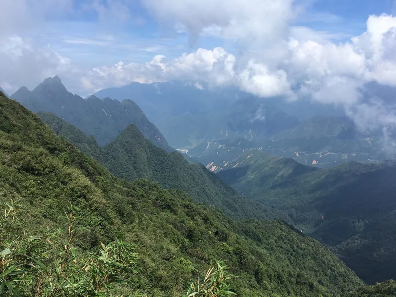 Jagged green peaks of the Hoang Lien Son mountain range rise beneath drifting clouds in Lai Chau.